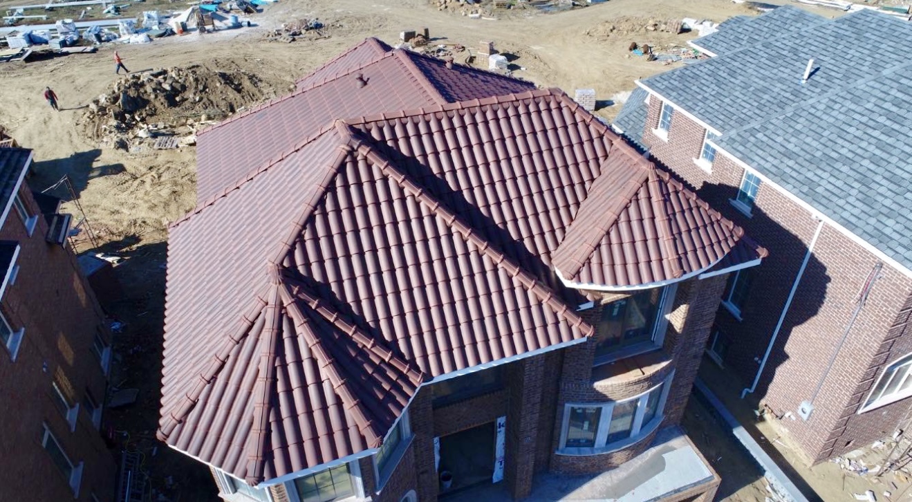 Top-down aerial view of maroon mission tile roof under construction
