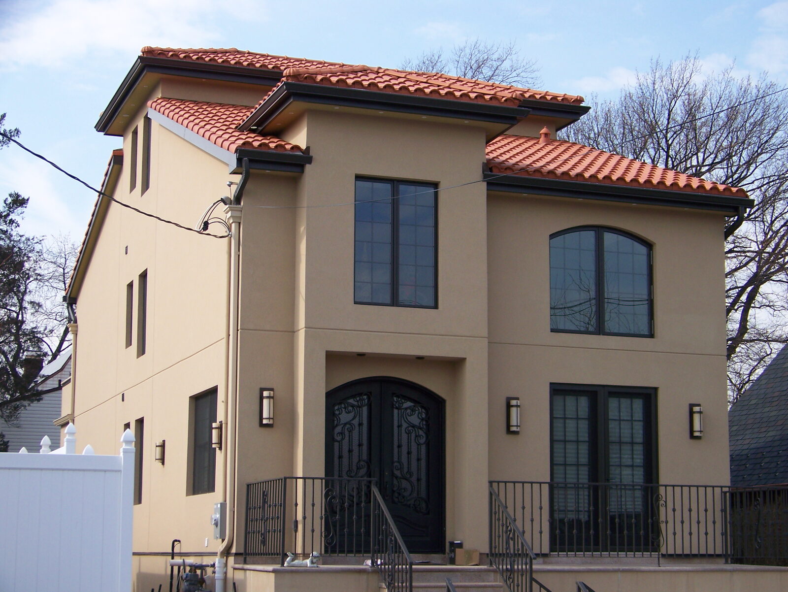Stucco home with black-framed arched windows and clay tile roof