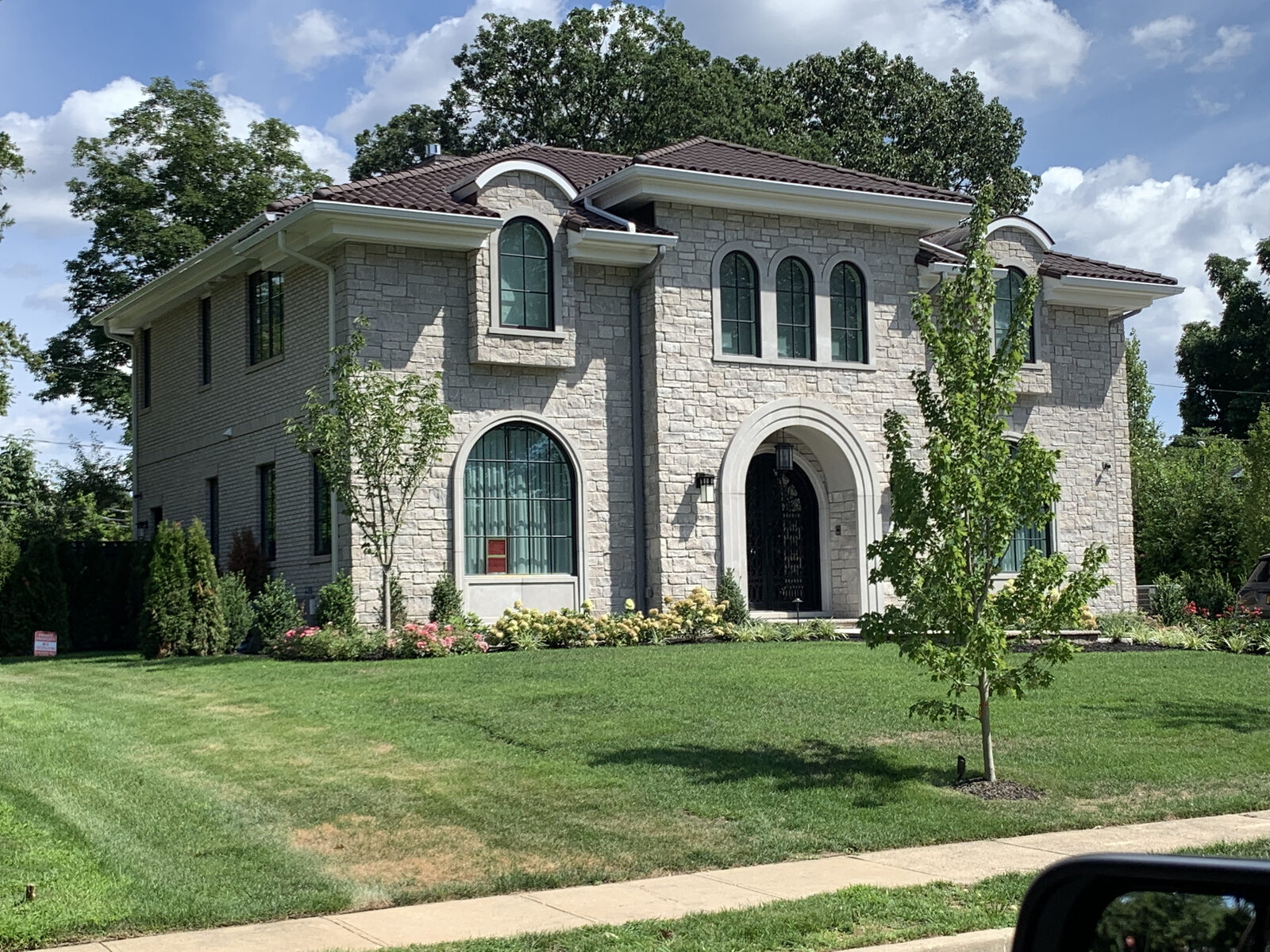Grey-stone home with arched entry and clay tile roof
