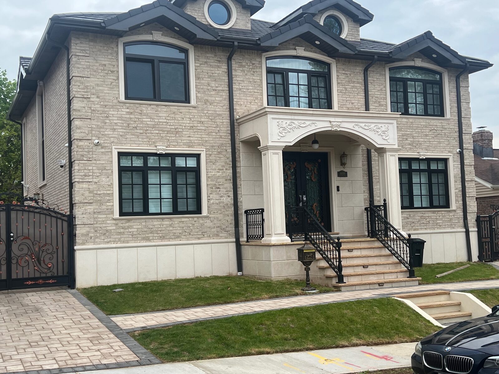Grey-stone hillside home with arched entry and clay tile roof