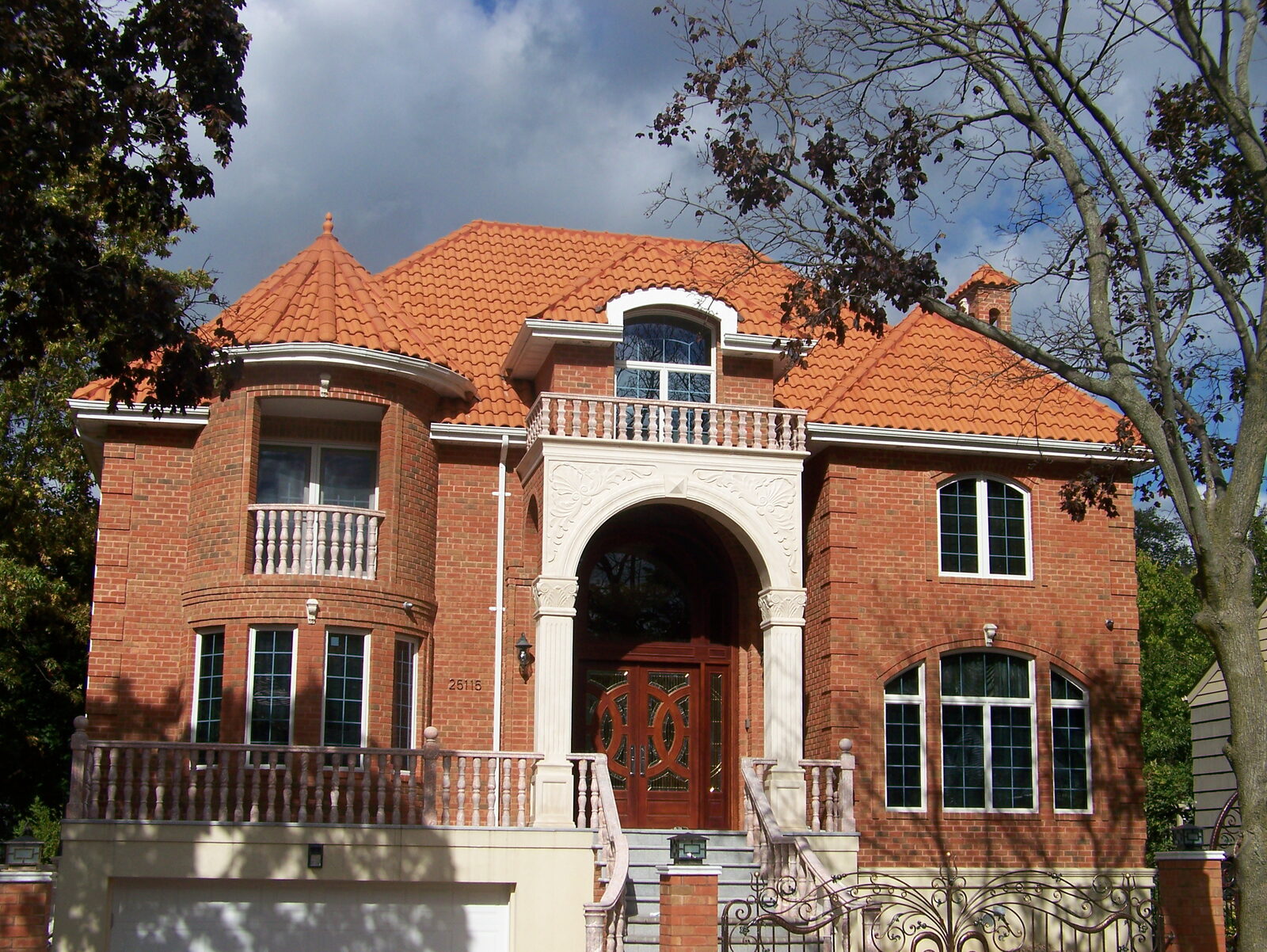 Grey-brick home with twin turrets and red clay tile roof