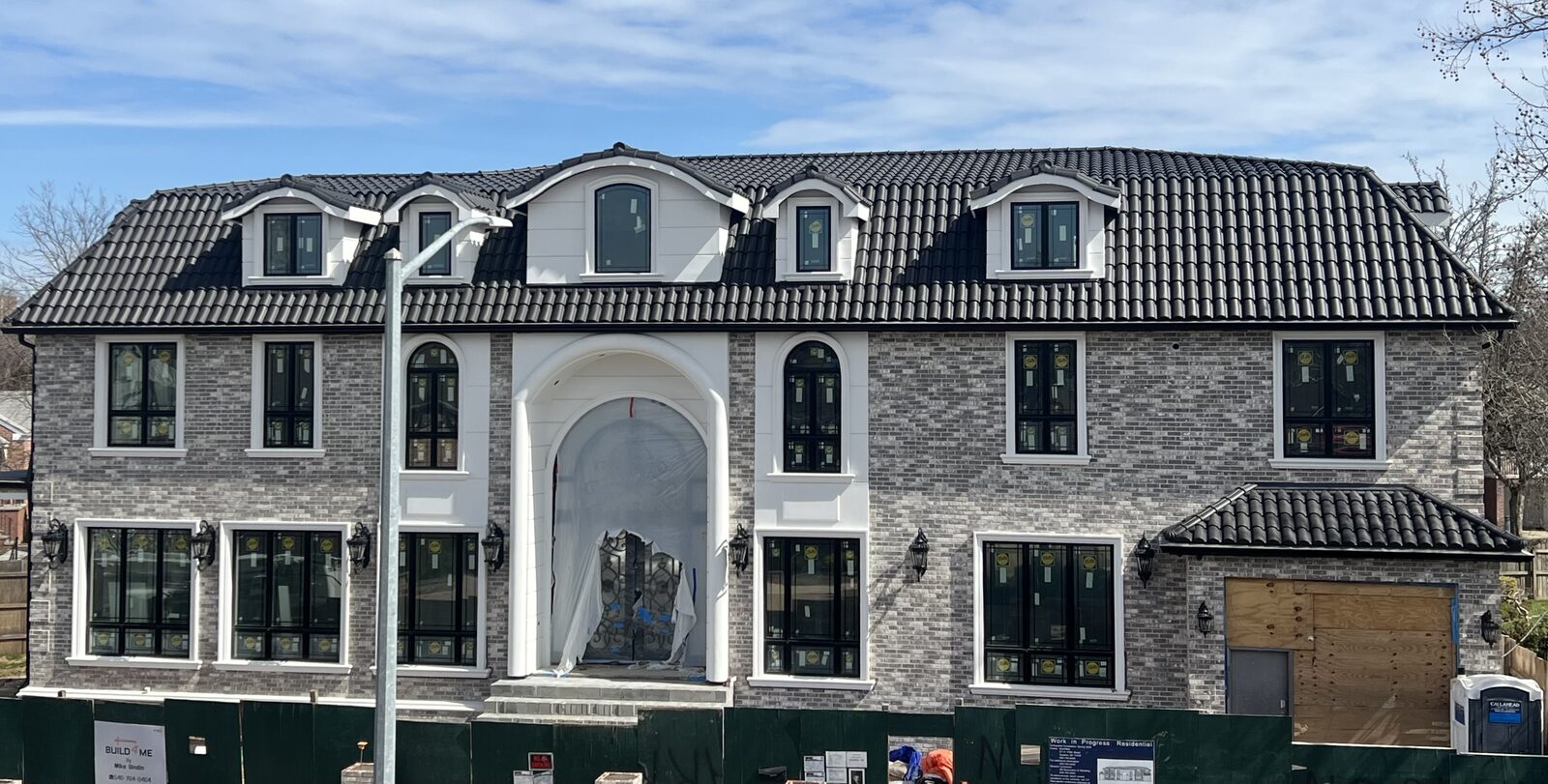 Grey-brick mansion with white trim and dark clay tile roof