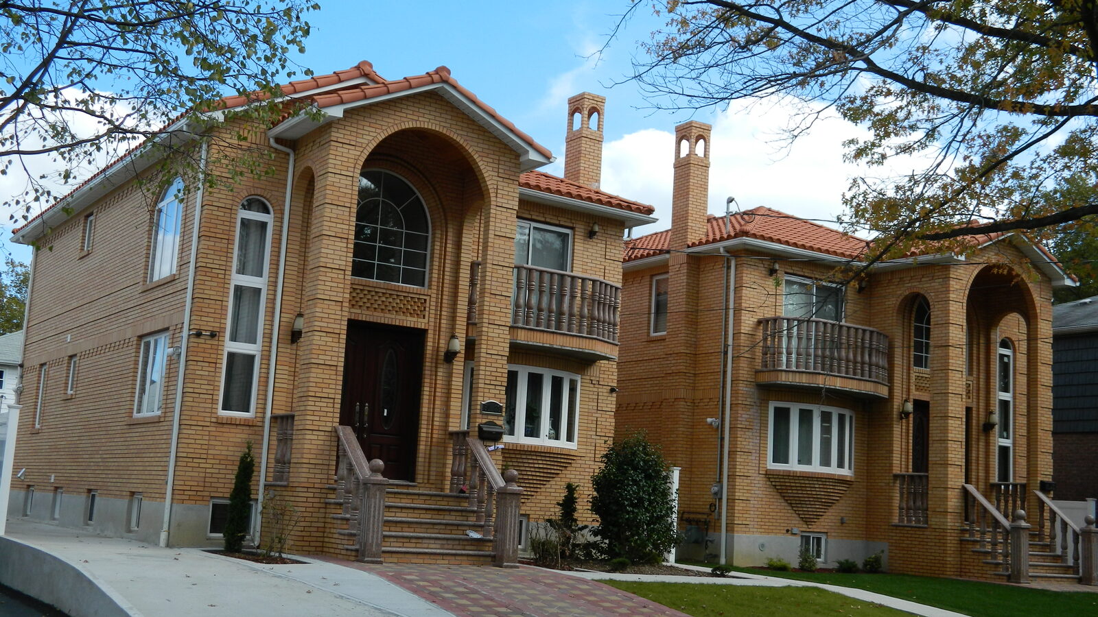 Golden-brick mansion with grand double staircase and clay tile roof