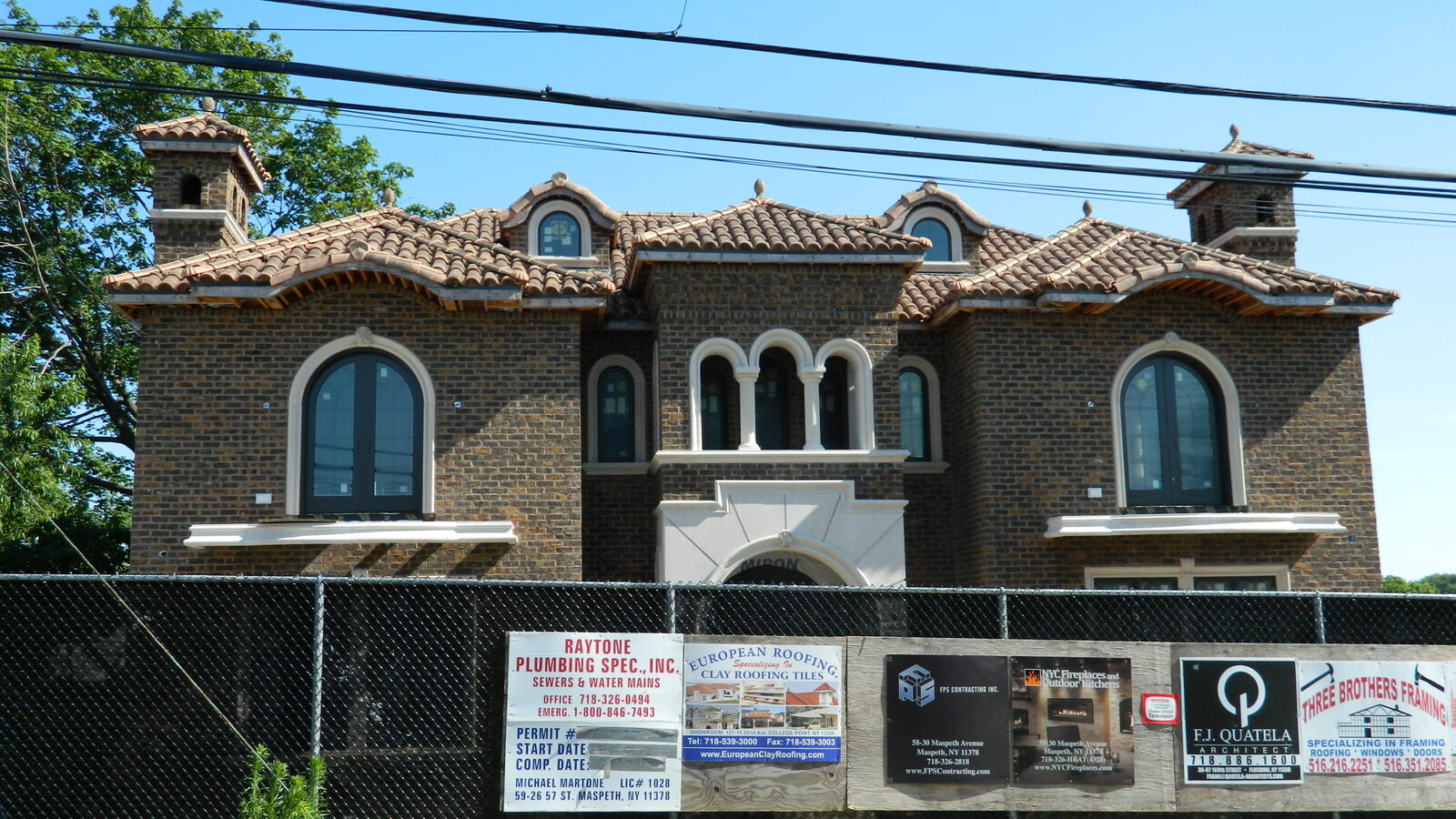 Dark-brick home with arched entry and clay tile roof