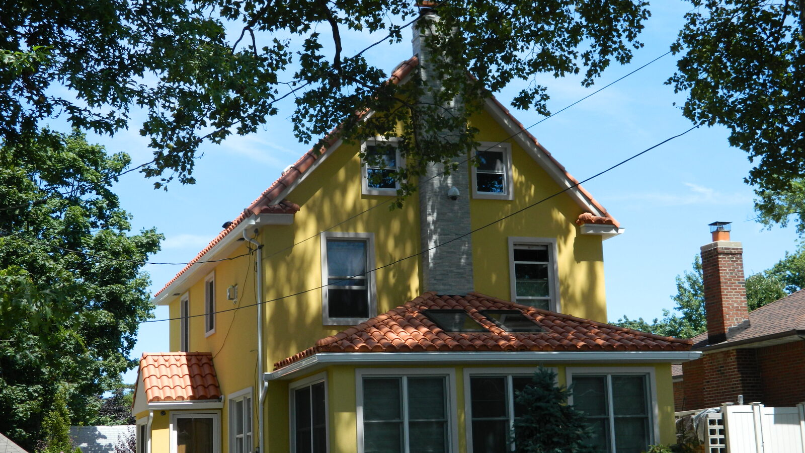 Yellow-stucco home with balcony and red clay tile roof