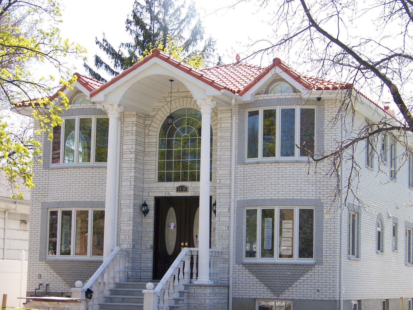 White-stone home with arched windows and clay tile roof