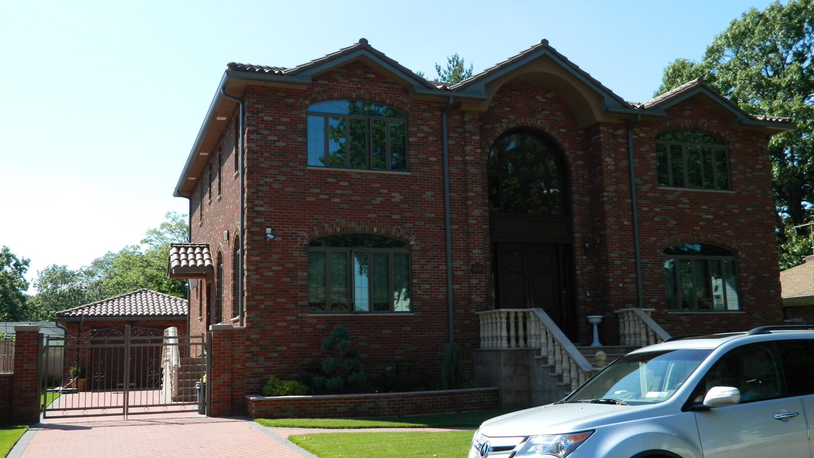 Dark-brick home with arched windows and clay tile roof