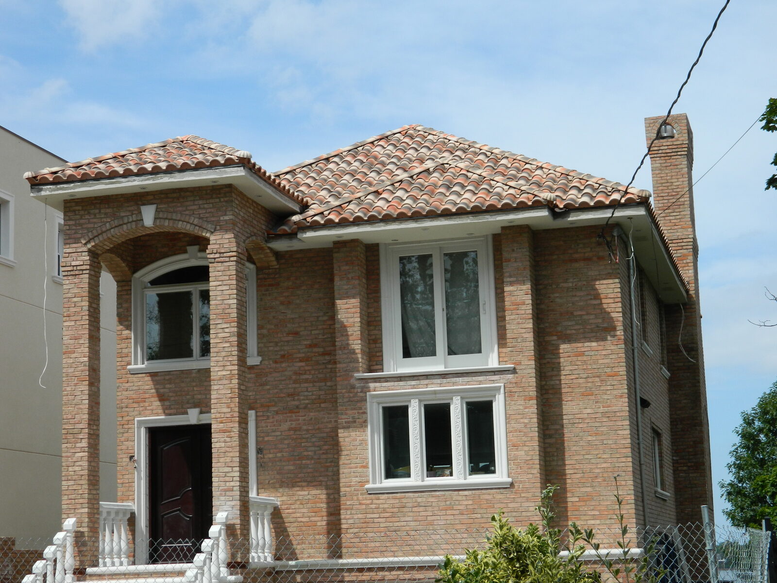Waterfront stucco home with red clay tile roof