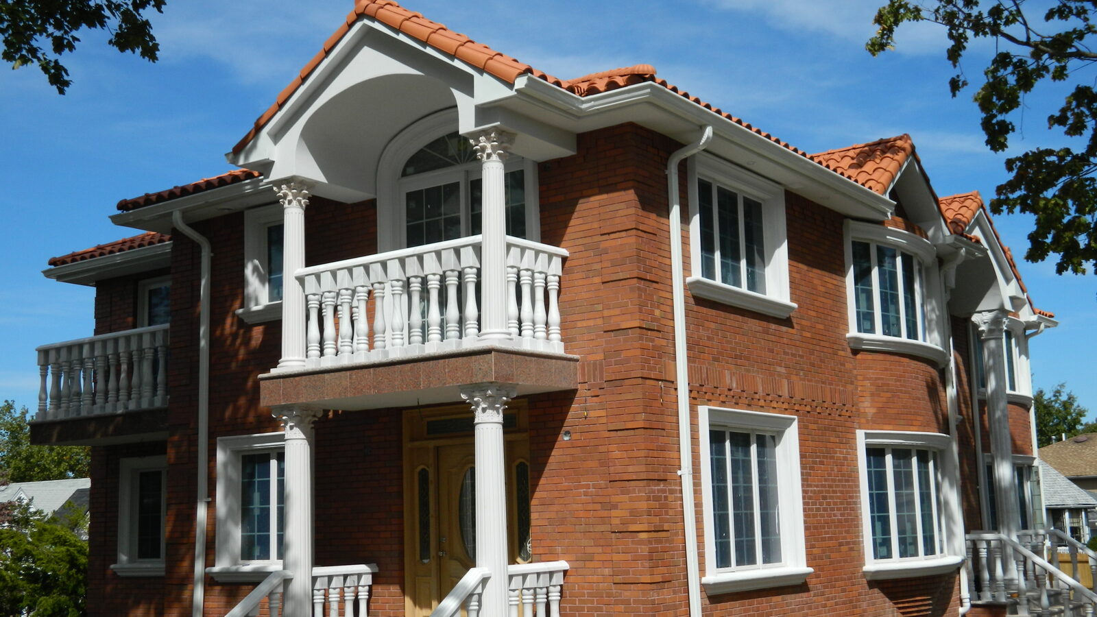 Brick home with balustraded balcony and clay tile roof