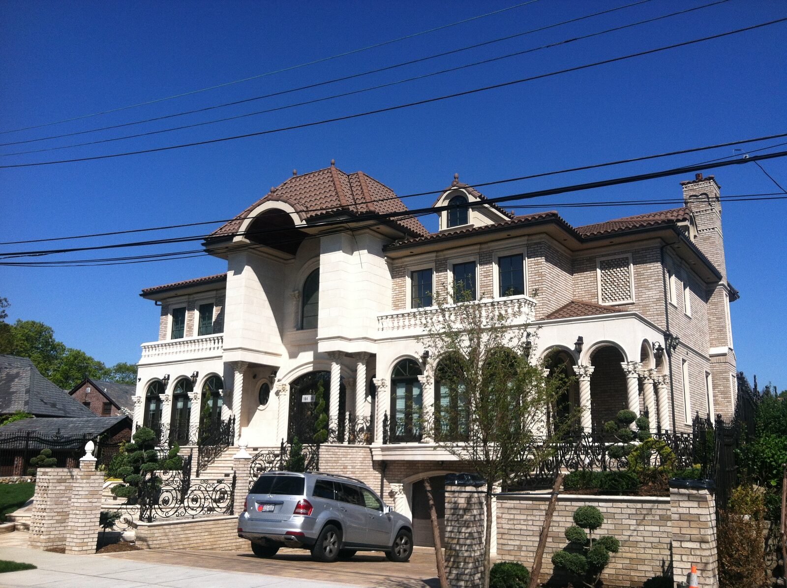 Cream-stucco mansion with double staircase and clay tile roof