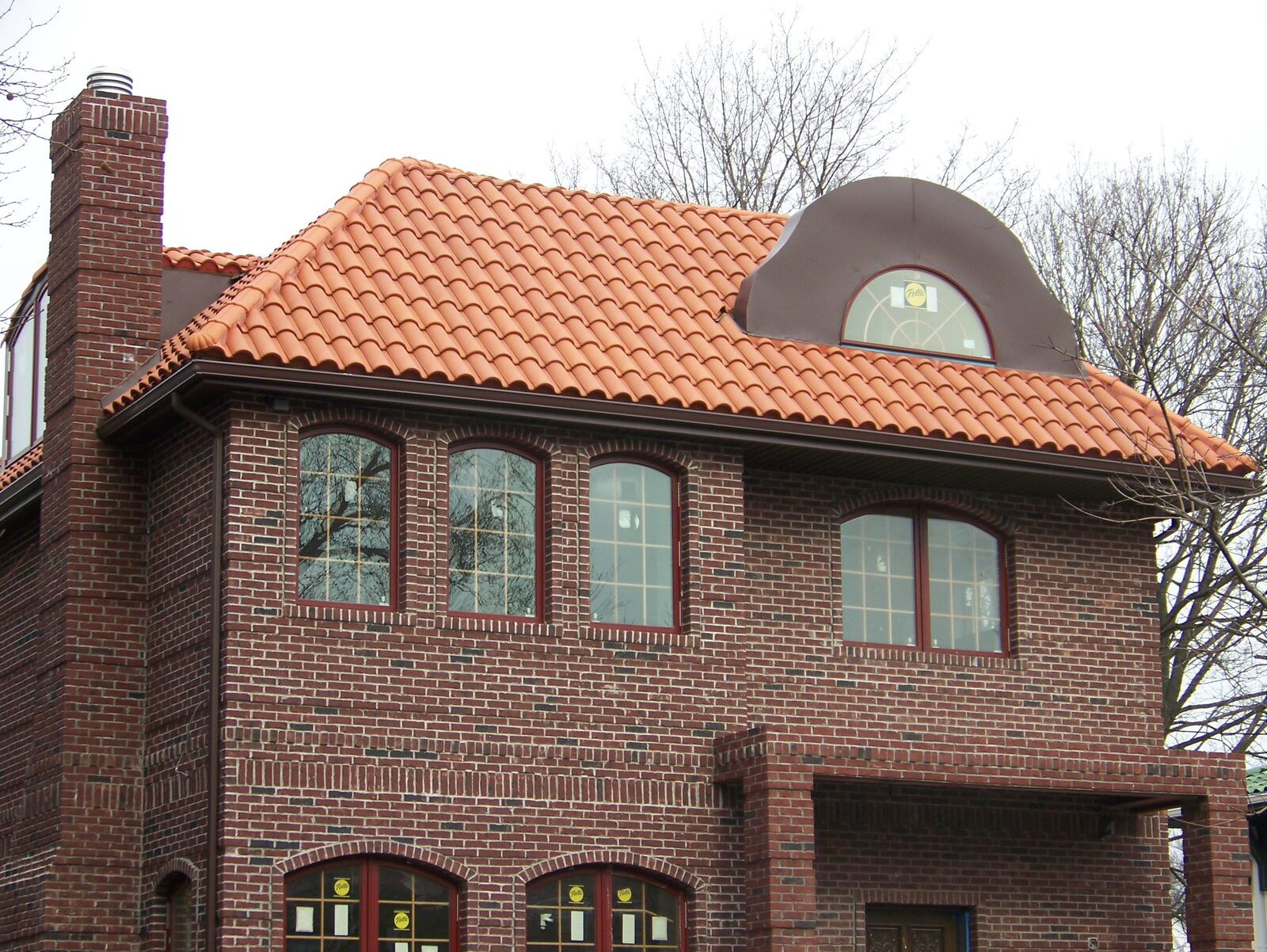 Brick home with dark-red clay tile roof and chimney