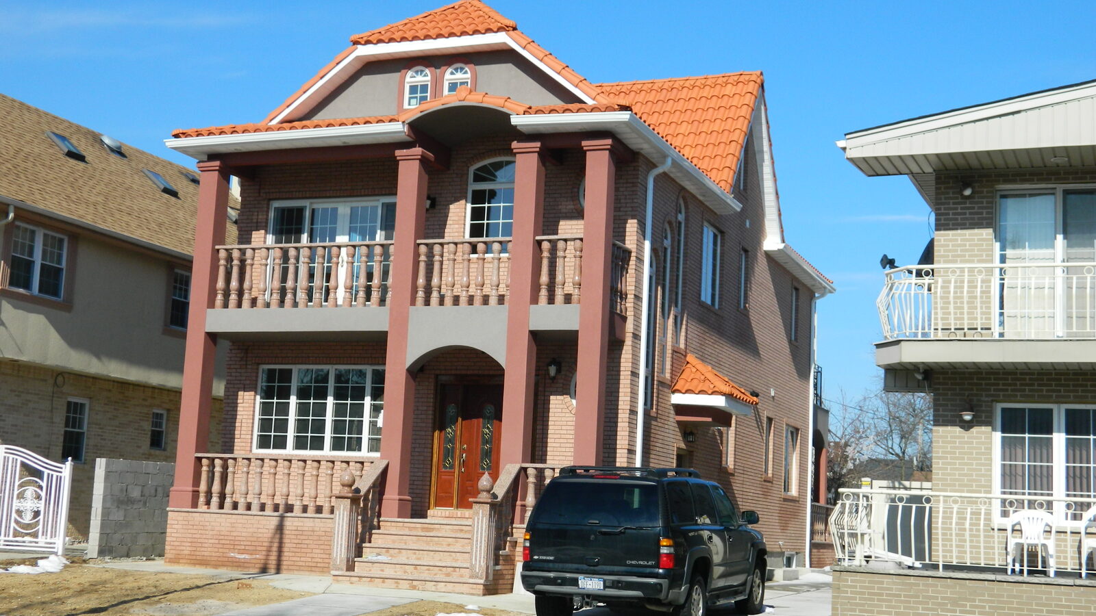 Salmon-stucco home with balconies and clay tile roof