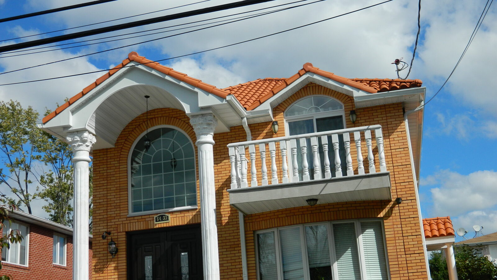 Orange-brick home with dormers and red clay tile roof