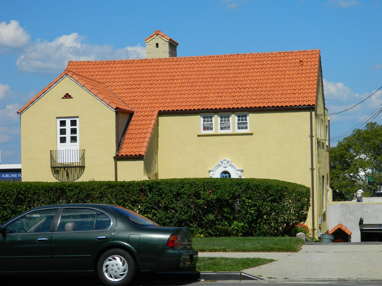 Stucco home with red clay tile roof and flowering tree