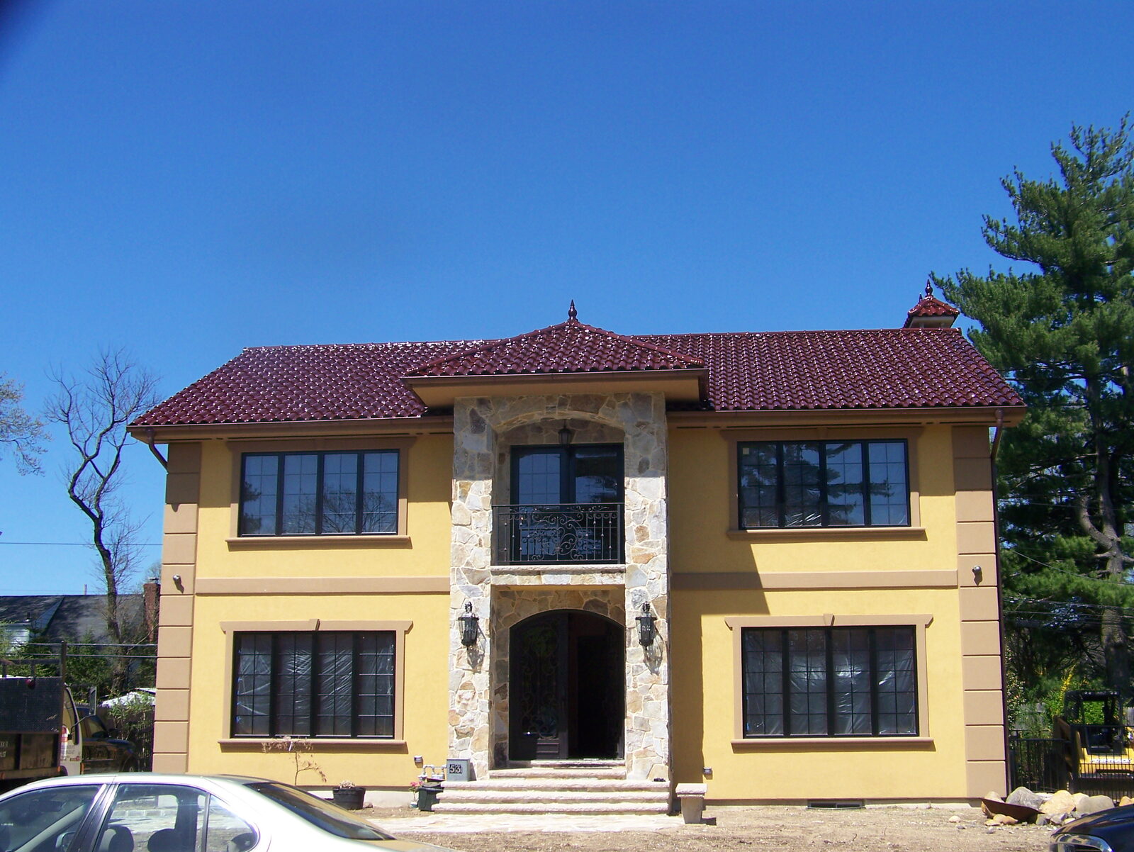 Golden-stucco home with stone entry and clay tile roof