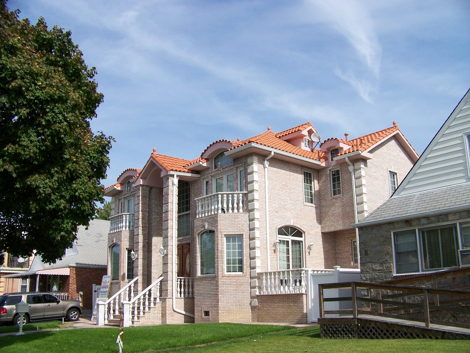 Golden-stucco mansion with arched entry and clay tile roof