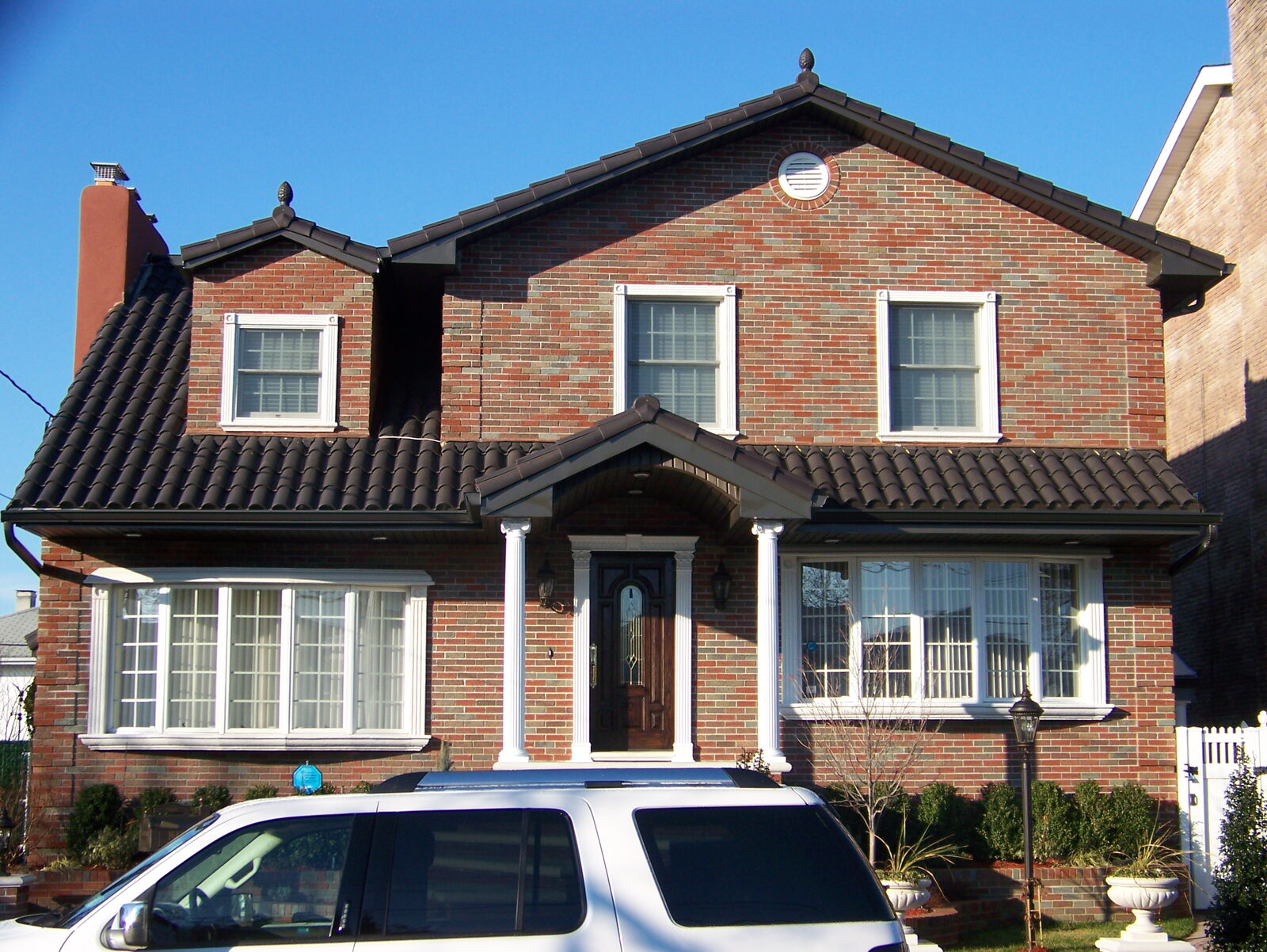 Brick home with dark clay tile roof