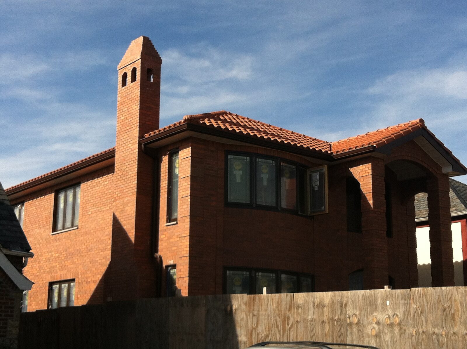 Brick home with tall chimney and red clay tile roof