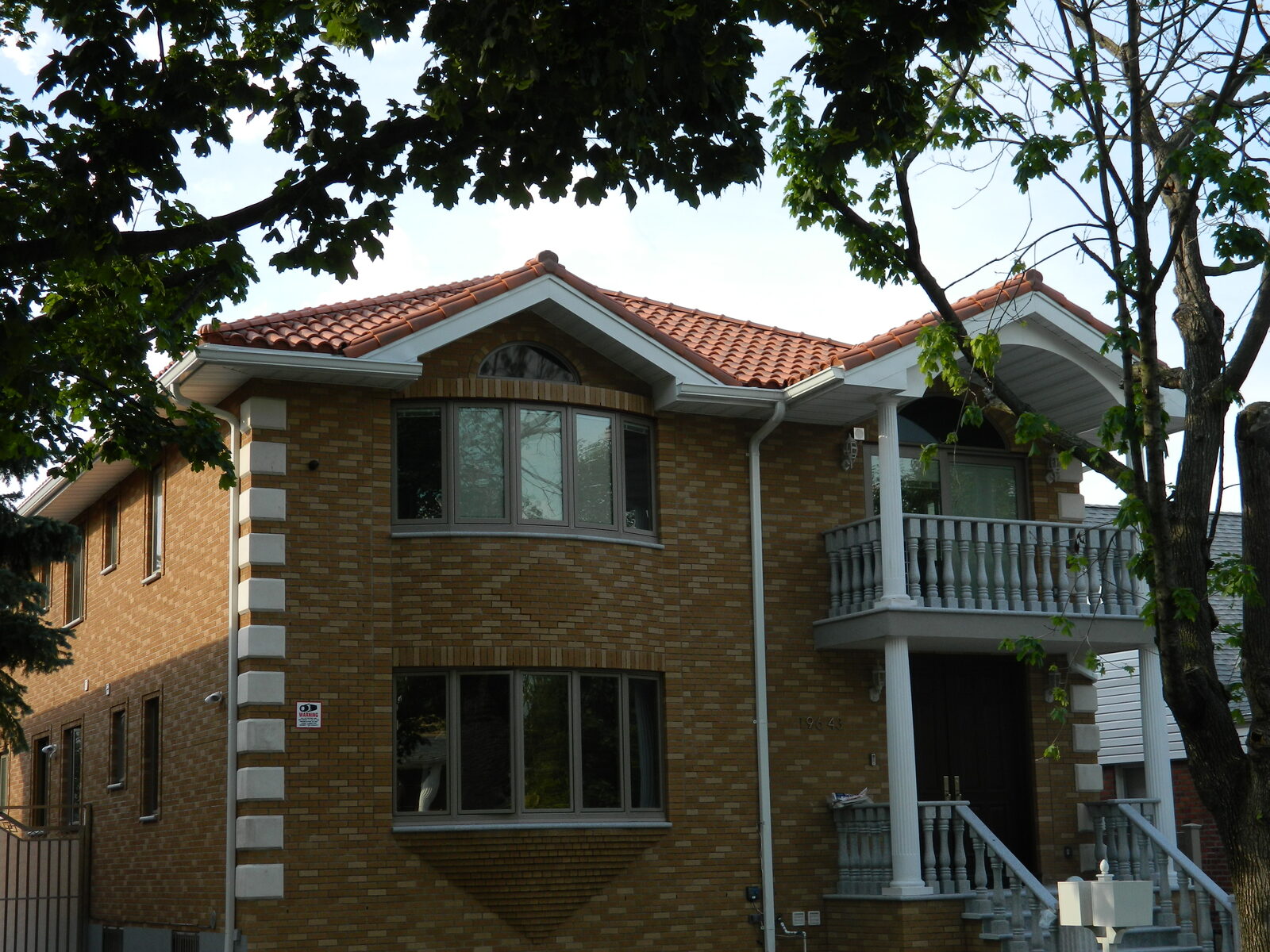 Brick home with red clay tile roof and manicured hedges