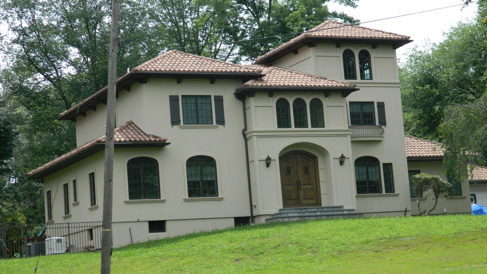 Stucco Mediterranean home with clay tile roof and green lawn