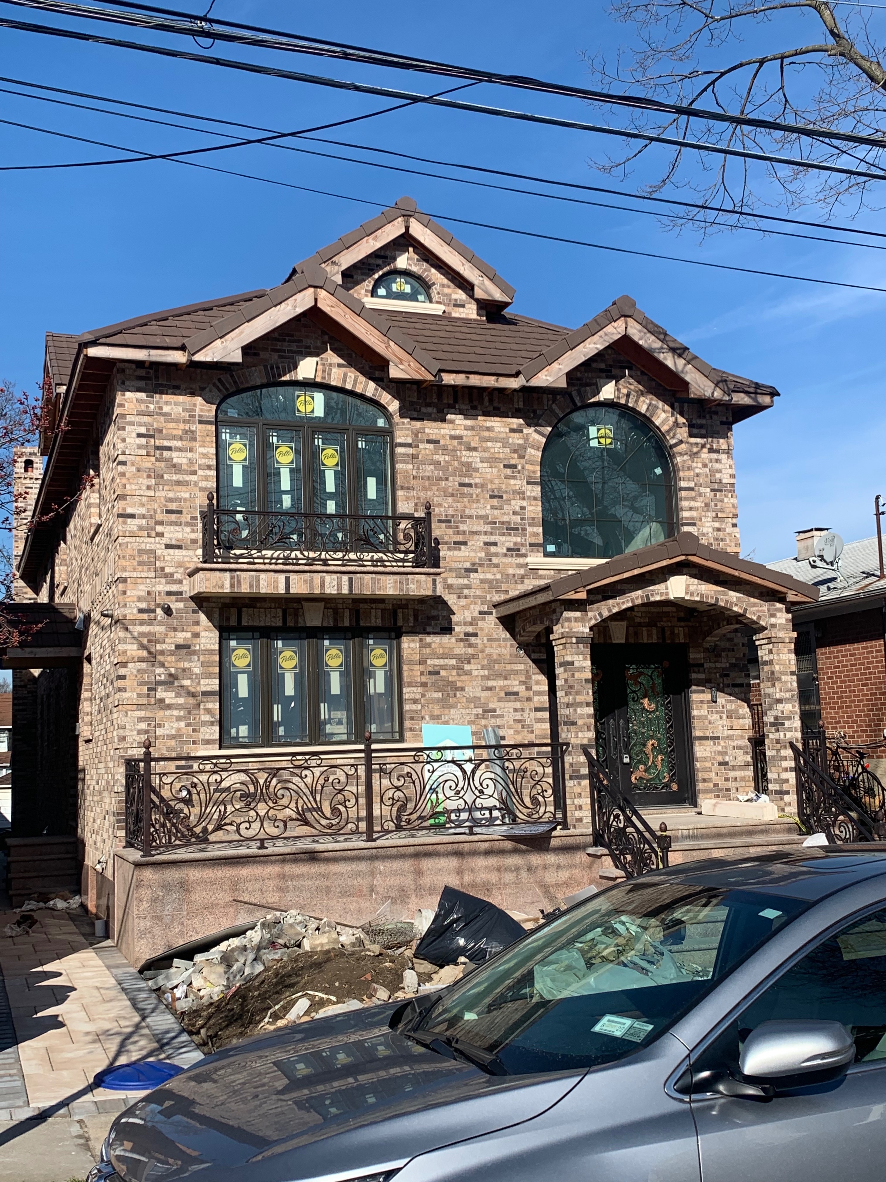 Elegant brick home with ornate ironwork and dark slate clay tile roof