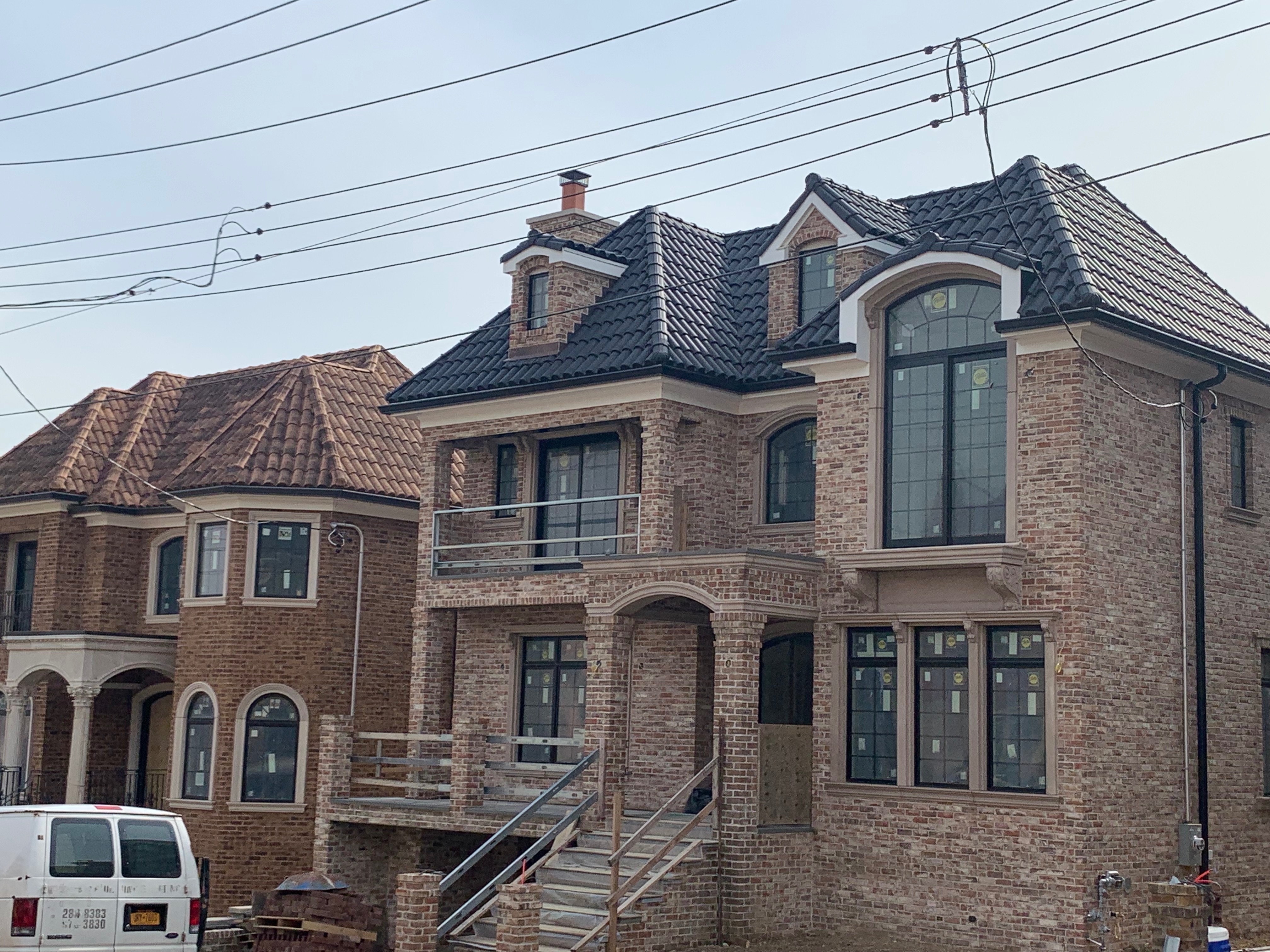 Two-story brick home with complex roofline and charcoal clay tiles
