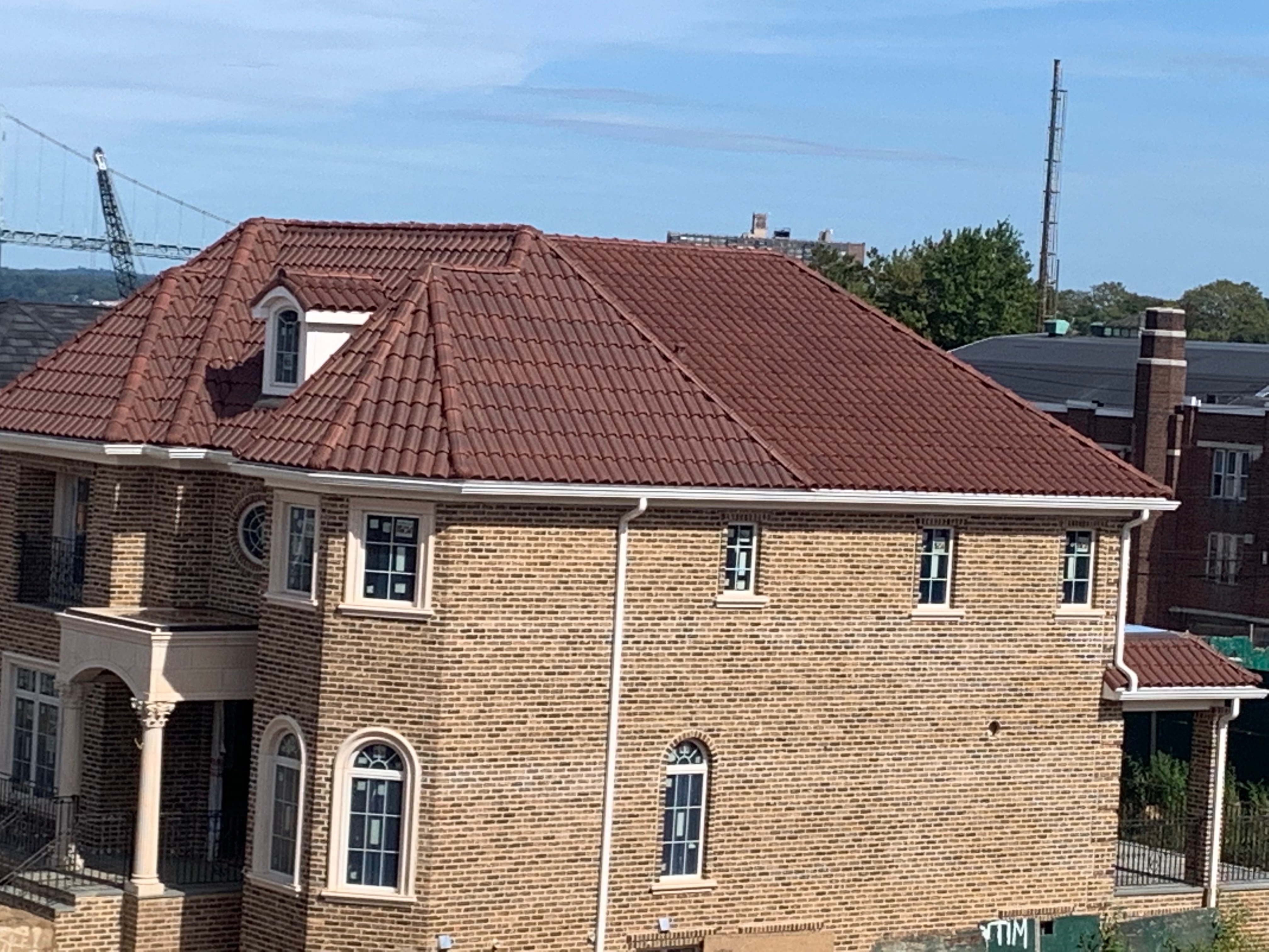 Aerial view of brick home with classic reddish-brown S-tile clay roof