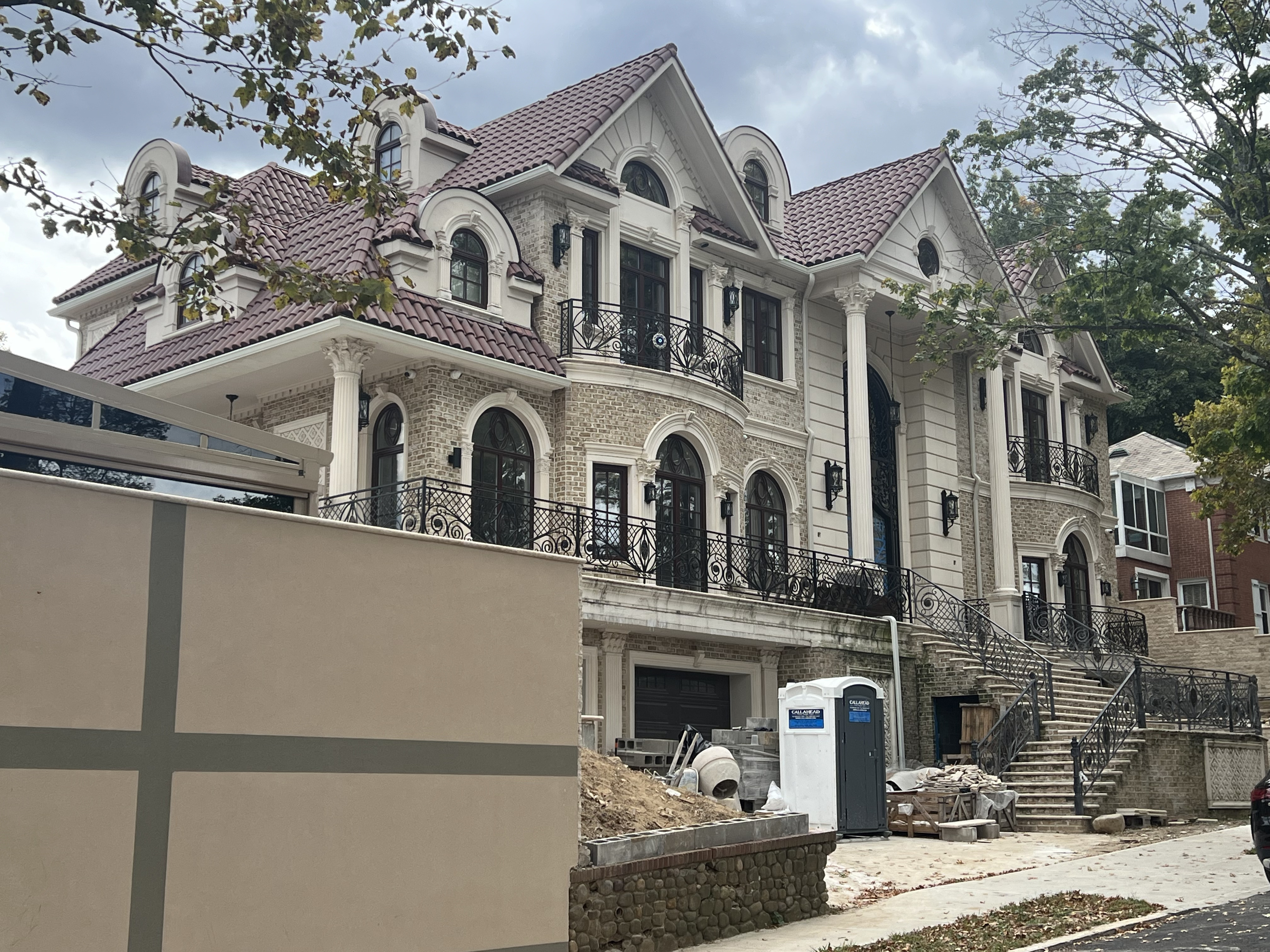 Luxury three-story home with classical architecture and reddish-brown clay tile roof