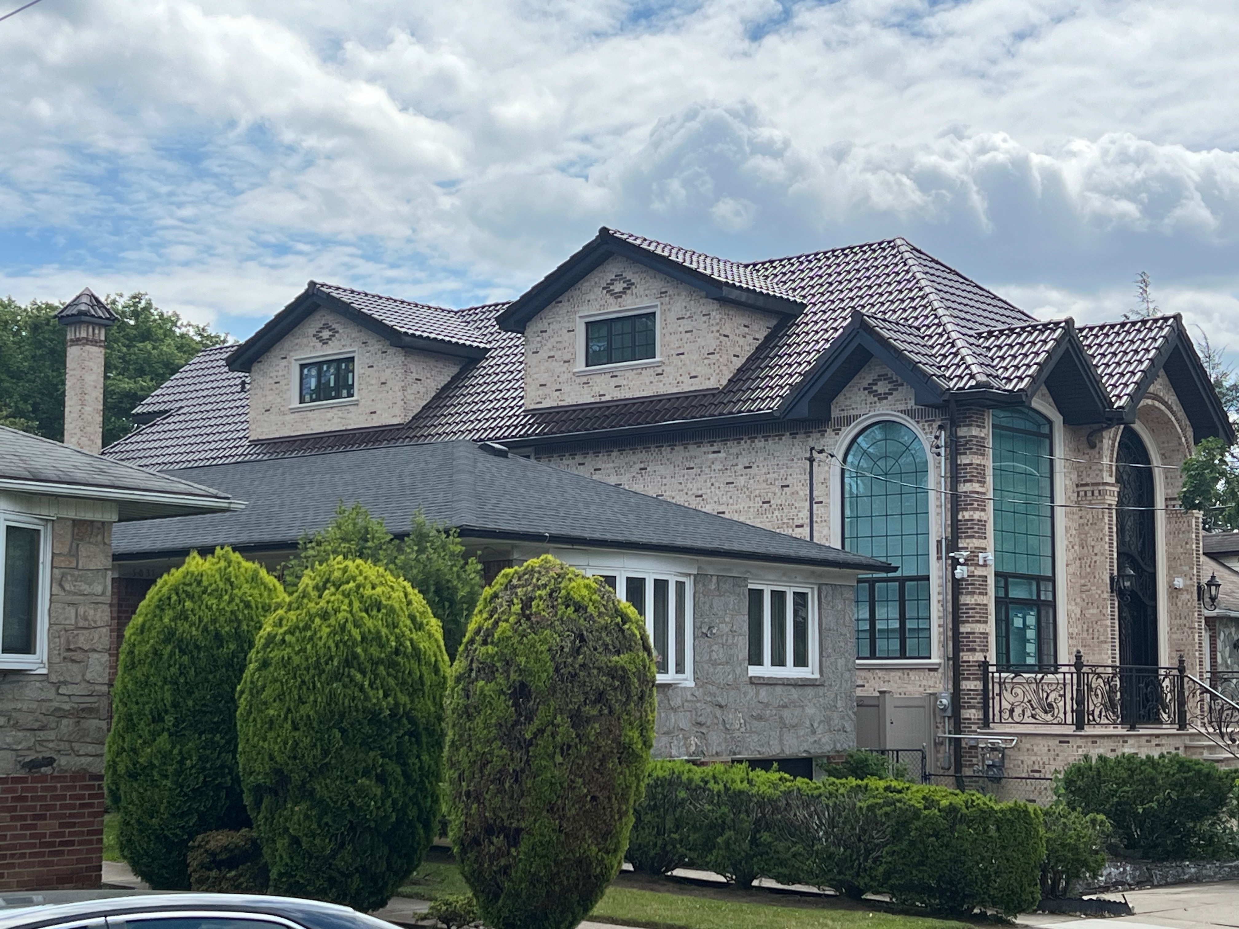 Large brick home with reddish-brown clay tile roof and multiple dormers