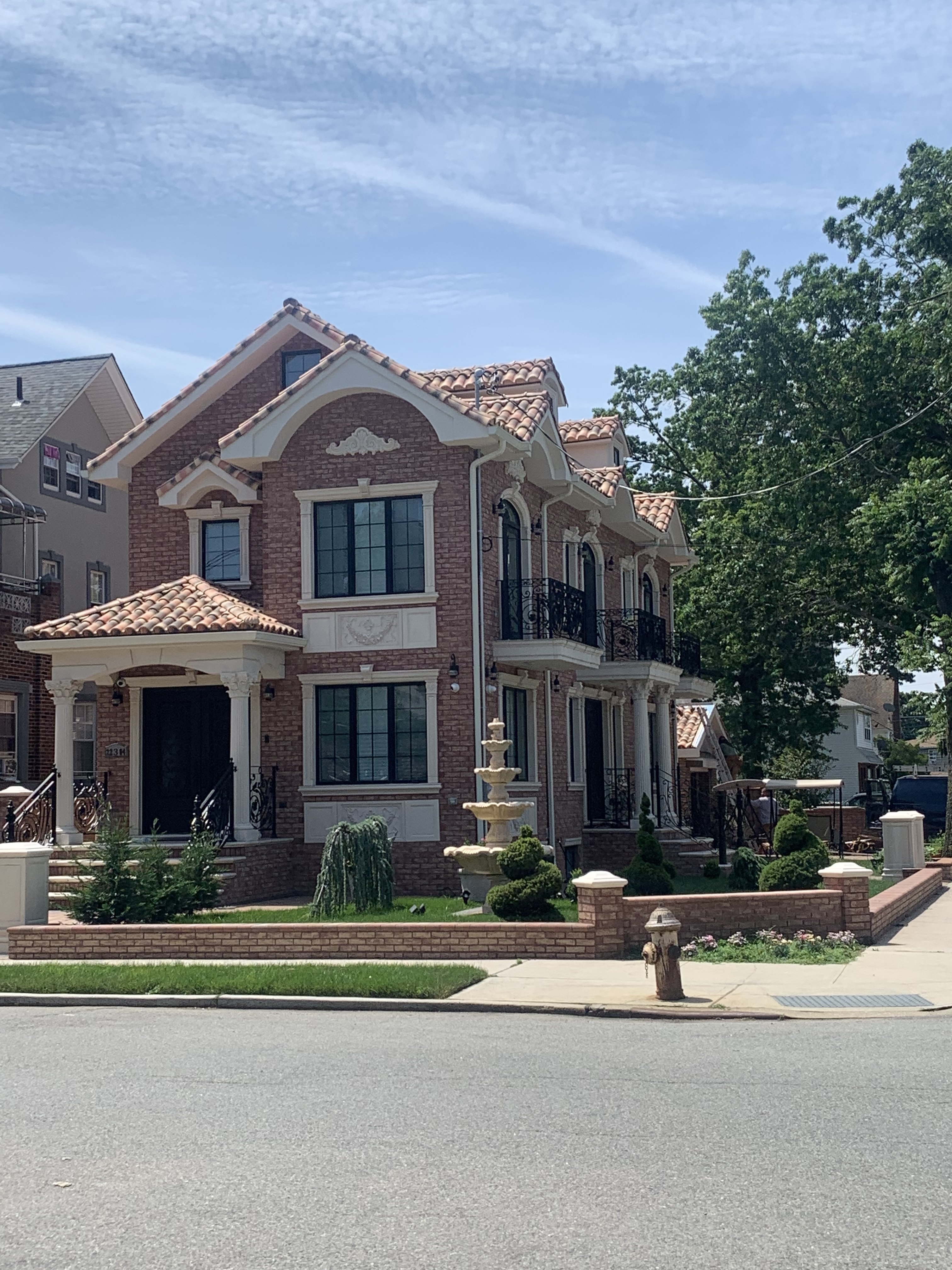 Elegant brick home with classic terracotta S-tile clay roof and decorative fountain