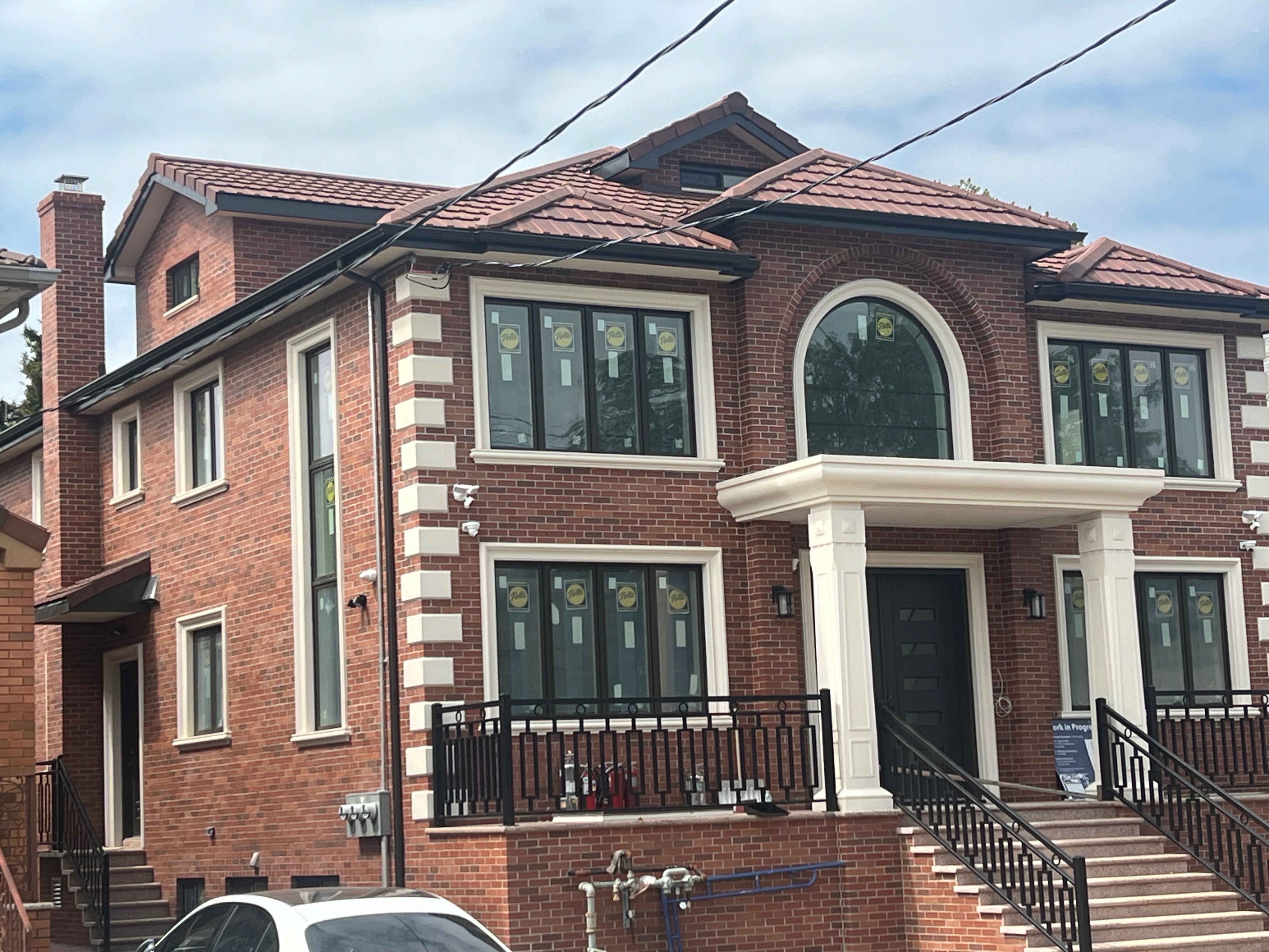 Two-story brick home with warm reddish-brown clay tile roof and arched windows