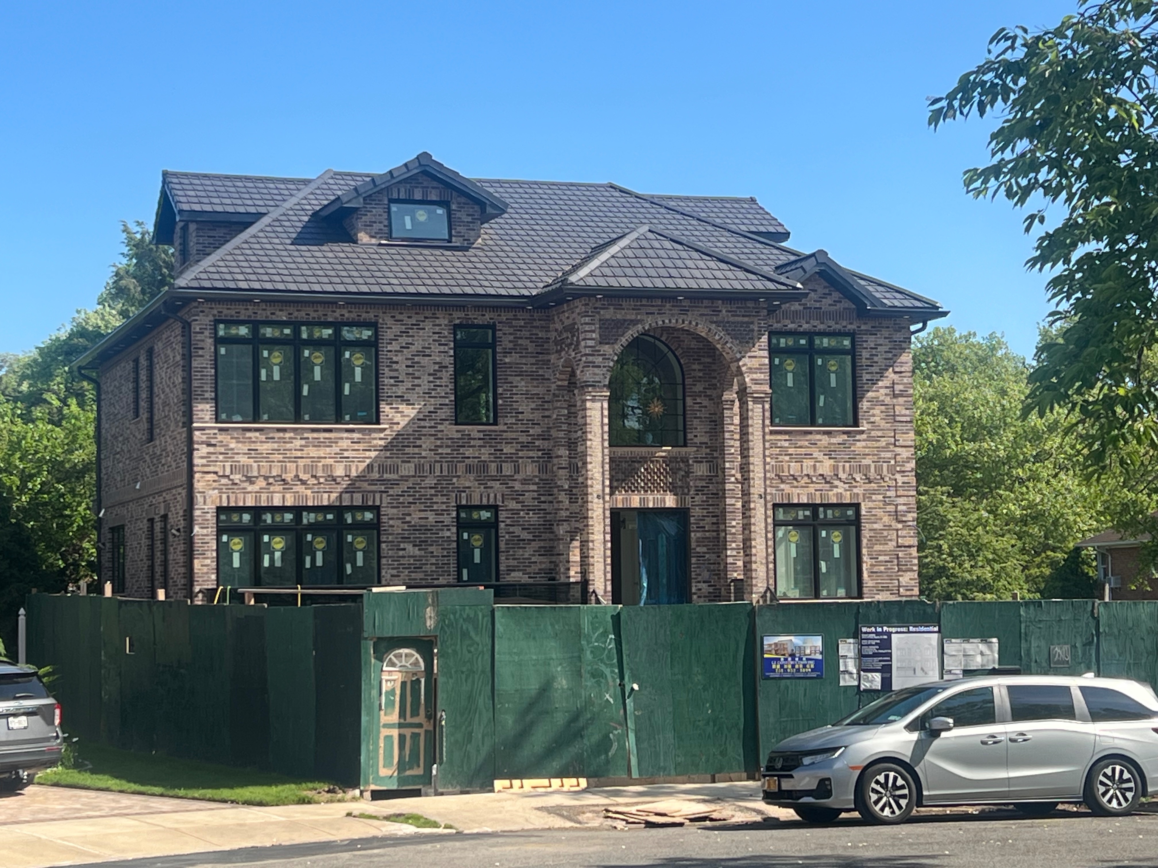 Large brick home under construction with warm brown clay tile roof installation