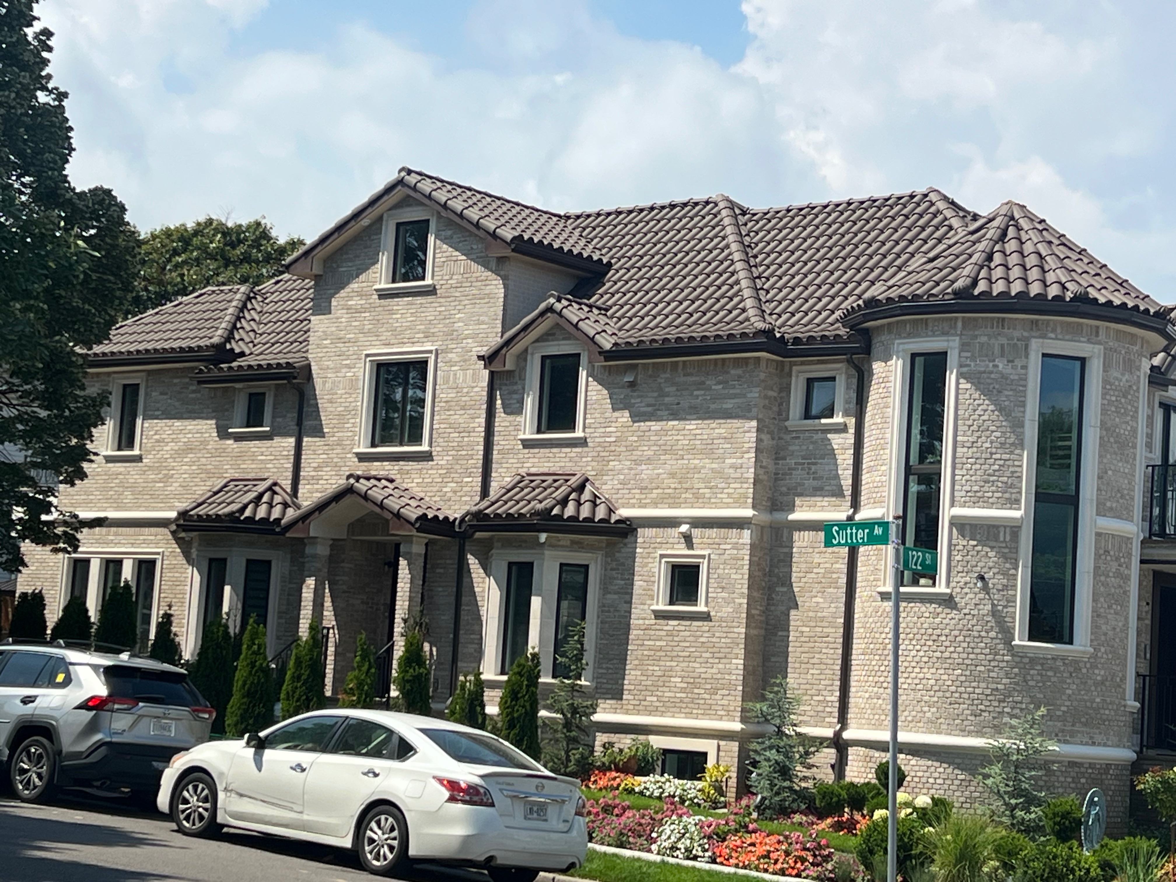 Large two-story home with light brick exterior and warm brown S-shaped clay tile roof