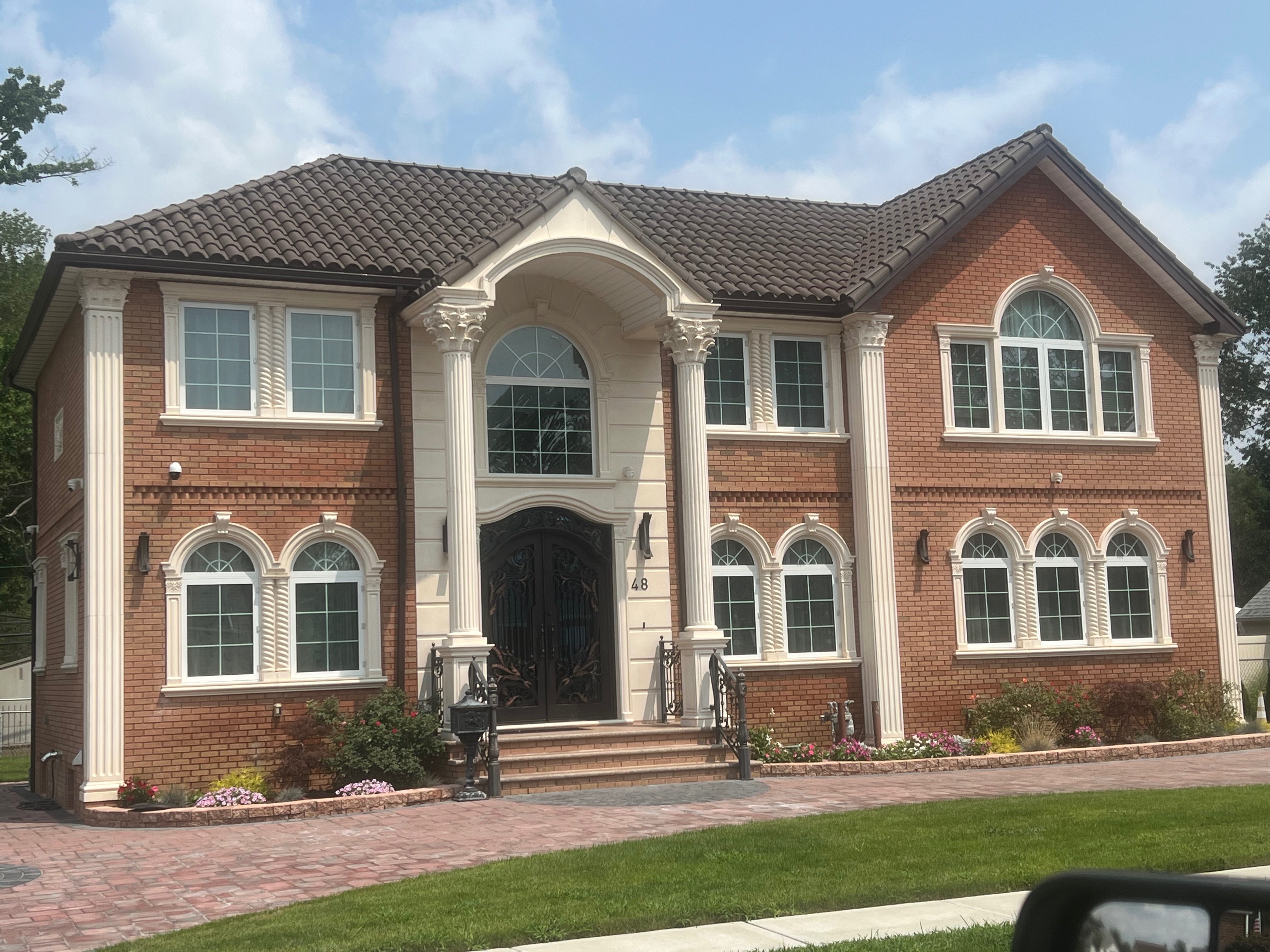 Elegant brick mansion with classical columns and brown cognac clay tile roofing