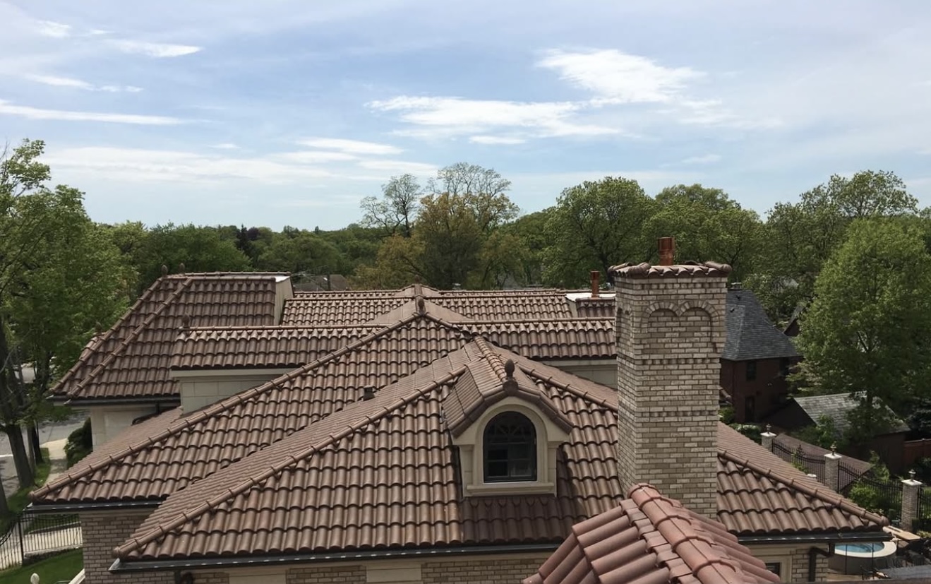 Aerial view of luxury home with extensive warm brown S-shaped clay tile roofing and multiple dormers
